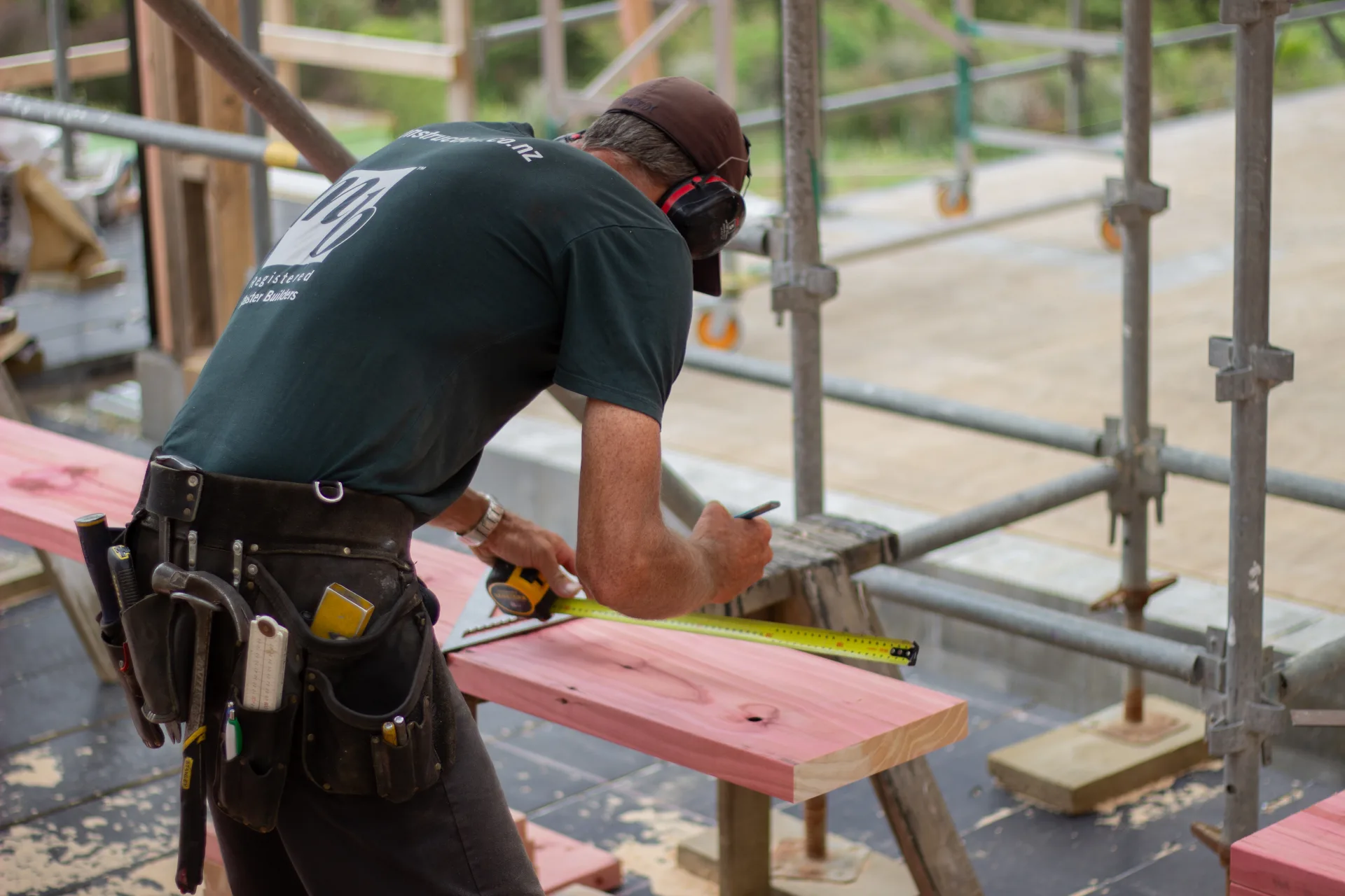 NF Construction builder measuring timber on a coastal build site